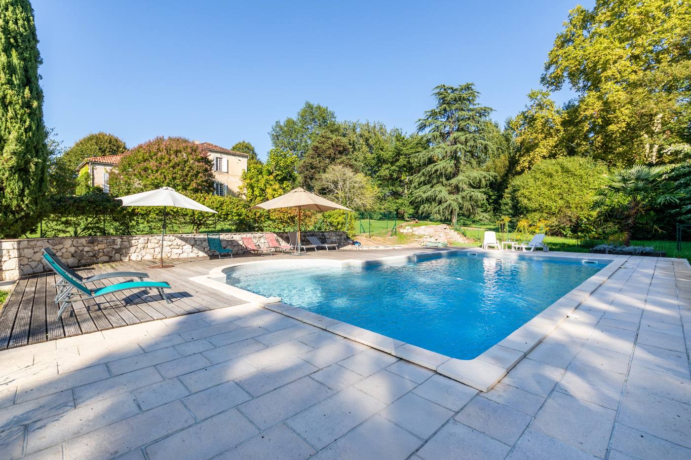 La piscine, ses transats et la maison au fond